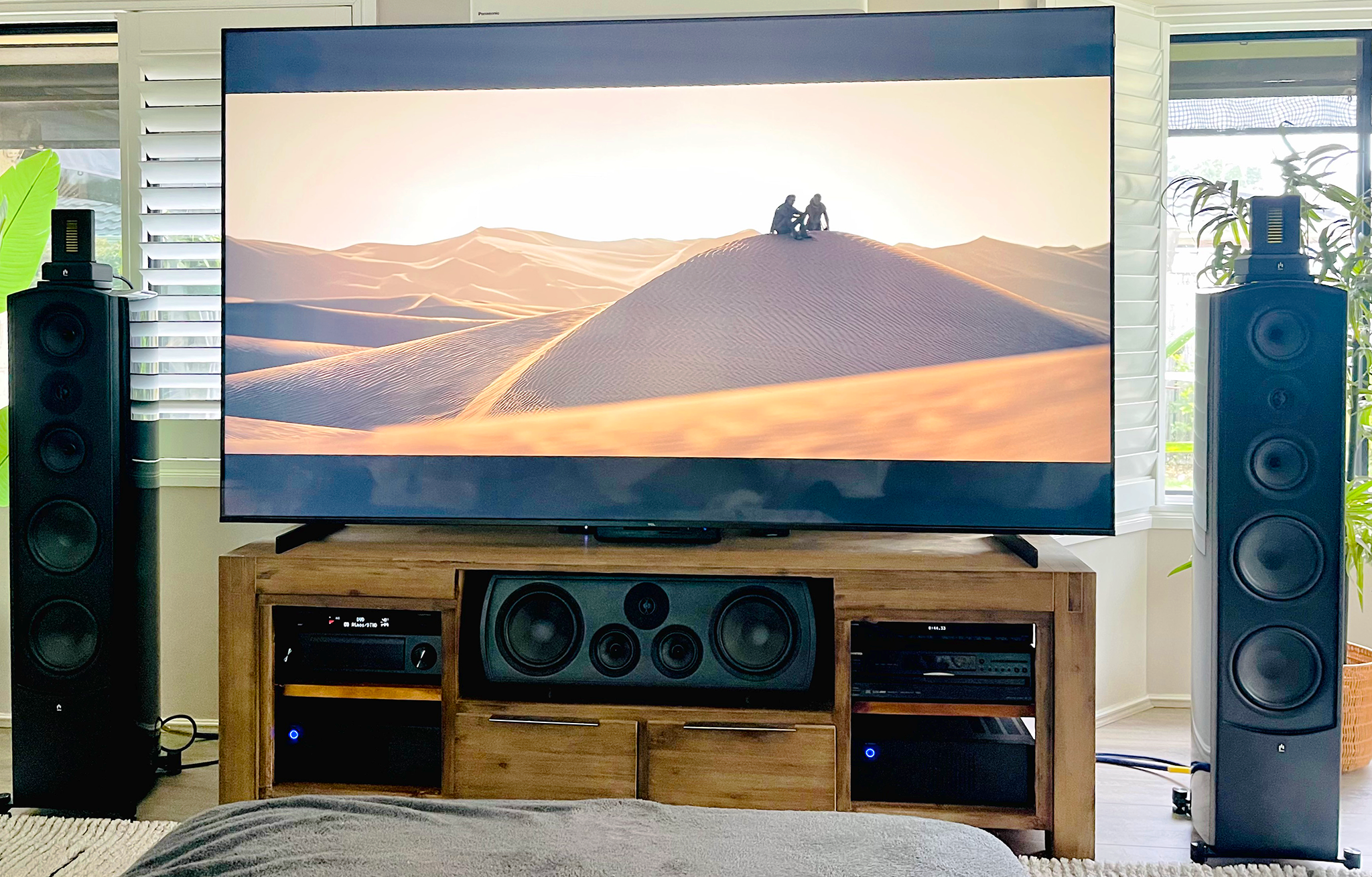 TV on a wooden stand with speakers in a living room setting