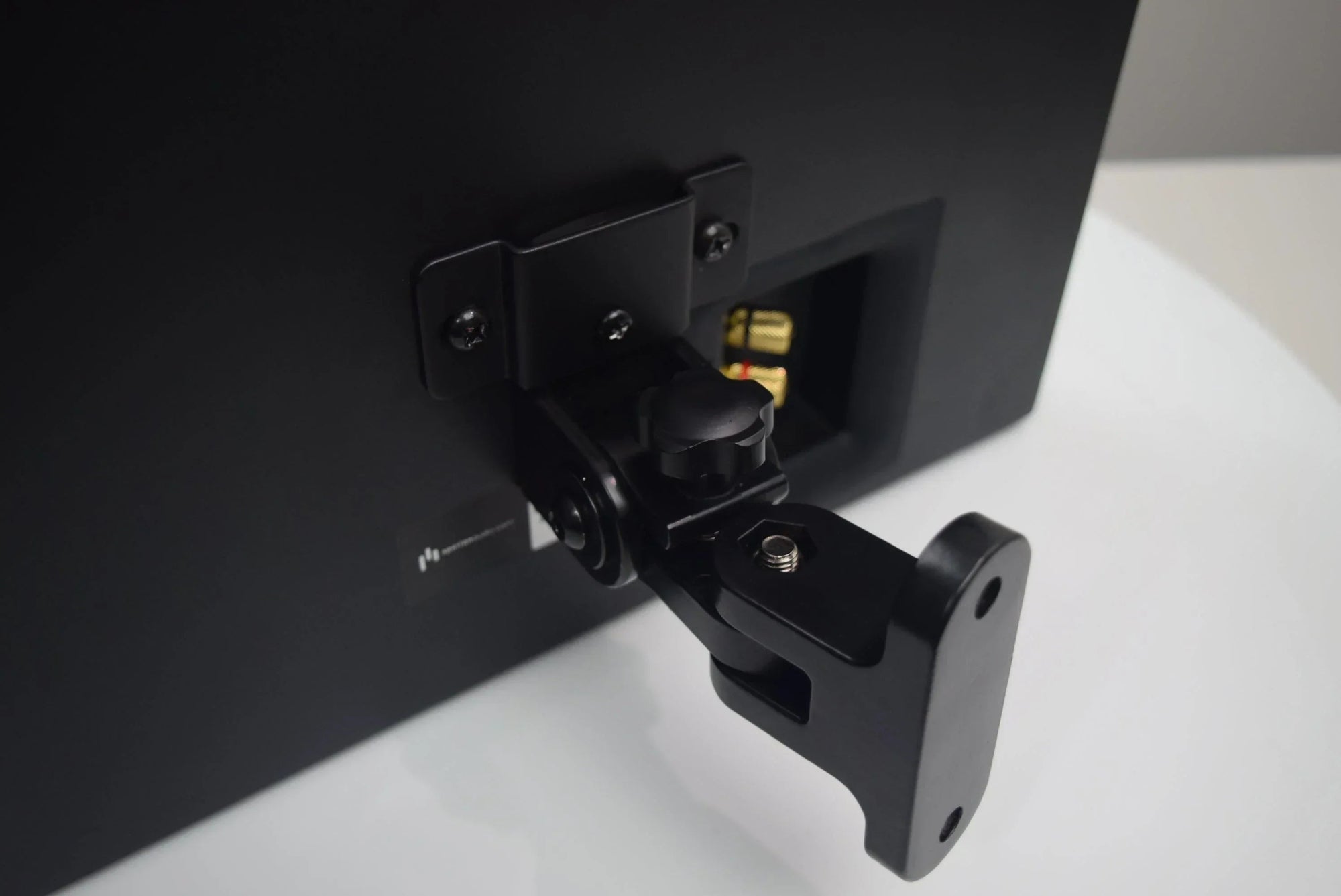 Aperion Audio Swivel Mount Attached to a Novus speaker on a white and grey background